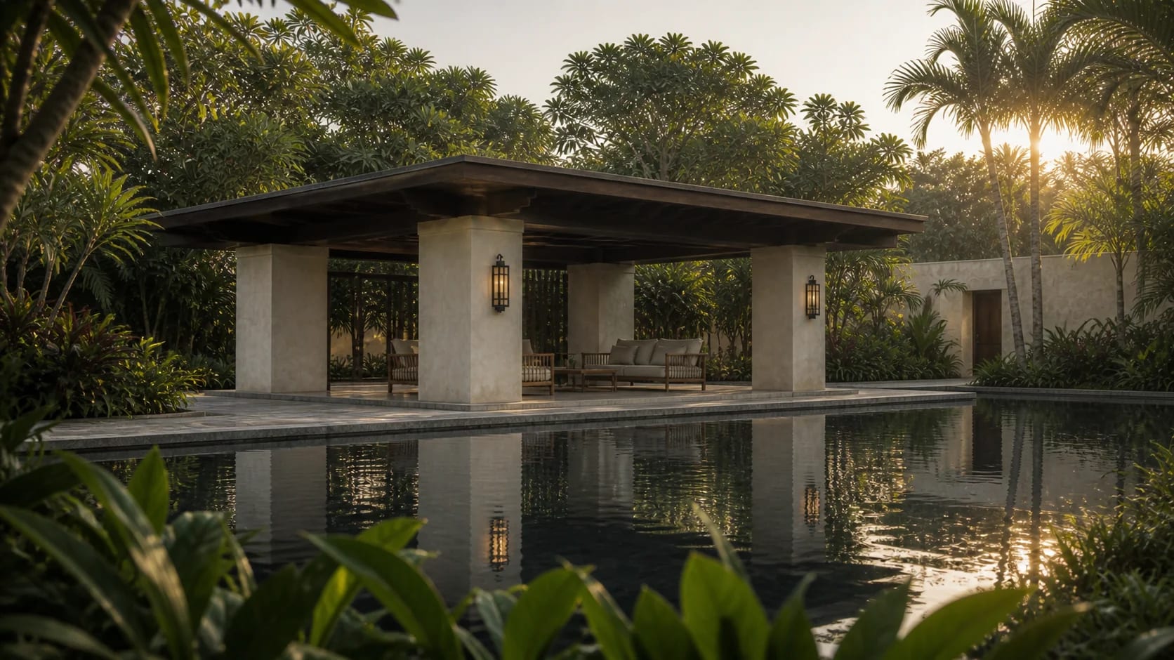 Pabellón de piedra y estuco con salas lounge, reflejado en un espejo de agua en calma al atardecer, entre palmeras y follaje tropical.